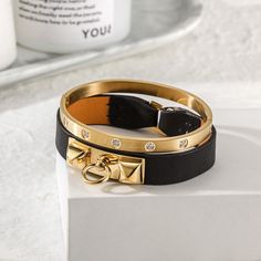 Sku: NSB1400GC-NSB1550STZD Details: Sleek and simple, this bracelet in leather with 14K gold plated. It is a statement-maker on its own or layered with other pieces. A great edition to an urban look or an informal outfit. This 14K gold/rose gold PVD bangle embellished with clear five of our best CZ stones. Arranged in an attractive and pleasing pattern, they catch the light from every angle. Our beautiful pieces are made of a metal that is hypo-allergenic which is great for those with sensitive Sleek Chic, Womens Bangles, Jewelry Candles, Jewelry Tags, Chic Leather, Urban Looks, Cz Stone, Black Handbags, Jewelry Designs