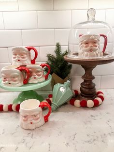 santa clause mugs under a glass clochet on top of a marble counter