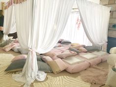 a bed with white drapes and pink pillows