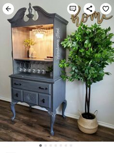 an old china cabinet painted gray with chalk lettering and a potted plant in the corner