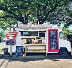 a food truck parked in front of a tree with signs on the side of it