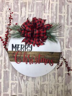 a merry christmas sign hanging on the side of a brick wall with red berries and greenery