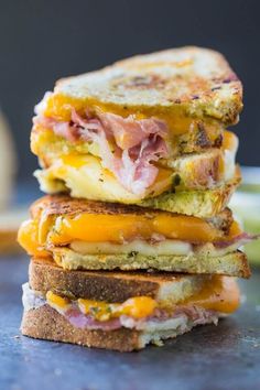 three sandwiches stacked on top of each other with cheese and ham in between them,