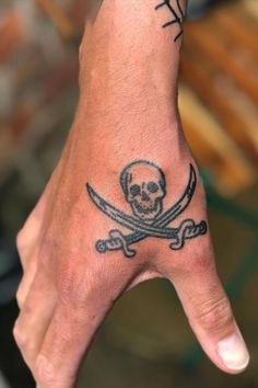 a hand with a skull and crossbones tattoo on it's left palm