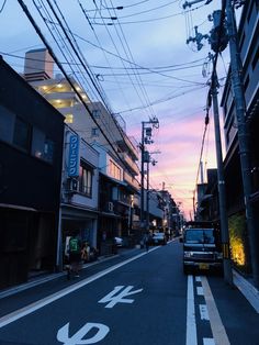 an empty city street at dusk with power lines above the road and buildings on both sides