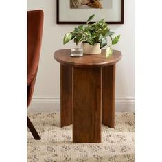 a wooden table with a plant on it in front of a chair and framed photograph