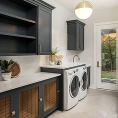 a washer and dryer are in the middle of a kitchen with dark cabinets