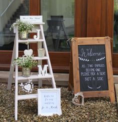 a white ladder with flowers on it sitting next to a sign and potted plants