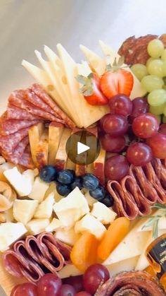 an assortment of cheeses, grapes and meats on a platter