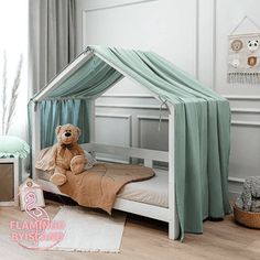 a teddy bear sitting on top of a bed in a room with white walls and wooden floors