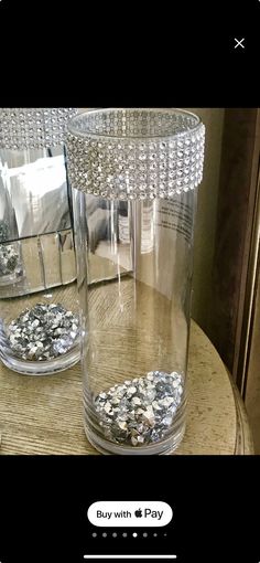 two clear glass vases sitting on top of a wooden table next to each other