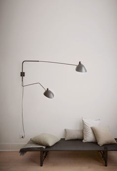 a couch with two lamps on the wall above it