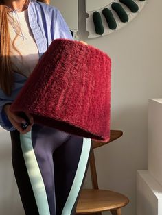 a woman sitting on a chair holding a large red object in her hand and wearing leggings