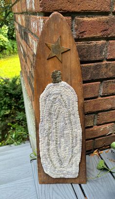 a wooden sign with a knitted sweater on it sitting next to a brick wall