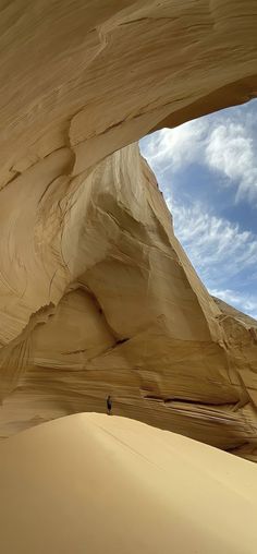 a person standing in the middle of an area with large rocks and sand, under a cloudy blue sky