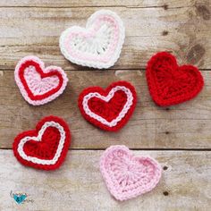 crocheted hearts are arranged on a wooden surface