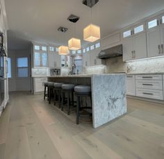 a large kitchen with marble counter tops and stools next to an island in the middle