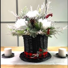 a basket filled with white flowers sitting on top of a table next to two candles