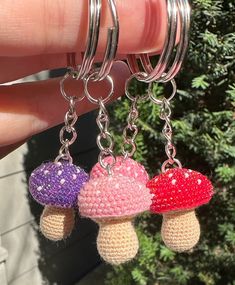 three small crocheted mushrooms are hanging from silver rings