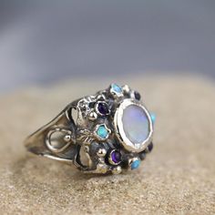 "A unique antique style hand crafted ring! A statement rainbow moonstone ring that will make you feel like a queen. This unique square signet features a sterling silver band and a round setting of a fascinating rainbow moonstone gemstone, and small lab opal and amethyst gemstones surrounding the center. Size: Moonstone signet ring is adjustable to any size, it has a small opening so you can adjust it to fit your finger. Measurements: Center stone - 10mm Small stones: 3mm Materials: Stone: moonst Queen Rings, Ring Moonstone, Magical Stones, Silver Signet Ring, Rainbow Moonstone Ring, Unique Antiques, Solid Gold Jewelry, Moonstone Ring, Sterling Silver Bands