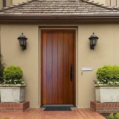 the front door of a house with two planters on either side and one light on