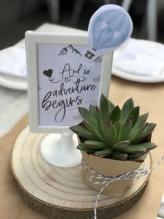 a small potted plant sitting on top of a wooden table next to a sign