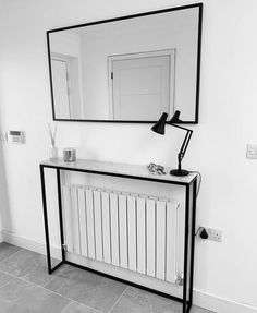 a black and white photo of a bathroom with a mirror, radiator and sink