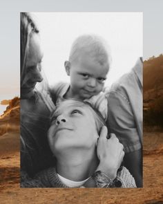 a black and white photo of a woman holding a baby in her arms with two other people looking on