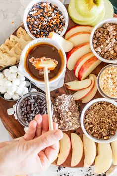 a person holding a wooden stick in front of an assortment of food on a tray