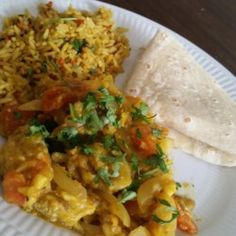 a white plate topped with rice, beans and veggies next to a tortilla