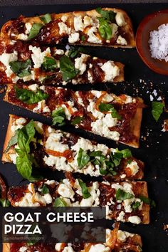 goat cheese pizza with basil and parmesan toppings on a black surface next to a bowl of sea salt