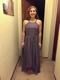 a woman standing in front of a door wearing a purple dress