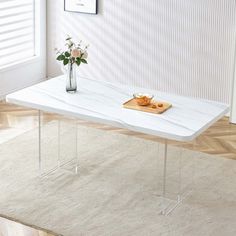 a white marble coffee table with clear acrylic legs and a vase on top