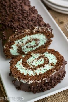 there is a chocolate roll with green frosting on the top and one slice cut out