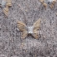 a close up of a knitted sweater with gold and silver decorations