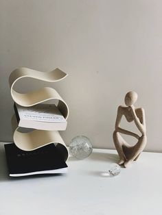 two sculptures sitting next to each other on top of a white table with a book