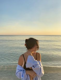 a woman standing on top of a beach next to the ocean