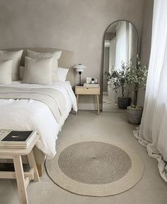 a bedroom with a bed, mirror and table in the corner on the floor next to it