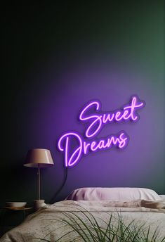 a neon sign that says sweet dreams on the side of a wall above a bed