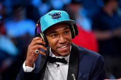 a man in a suit and hat talking on a cell phone while wearing headphones