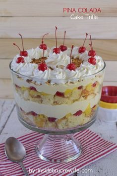 a trifle cake with white frosting and cherries in a glass dish on a red and white striped napkin