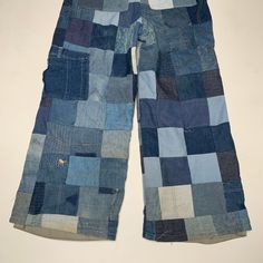 an old pair of jeans with patchwork on the bottom and sides, sitting against a white wall