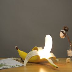 Banana Table Lamp: Whimsical Illumination Meets Modern DesignElevate your space with the Banana Table Lamp, a delightful blend of whimsy and modern design. This lamp, with its playful banana shape, is not just a lighting accessory but a conversation starter. Whether it's the cheerful yellow or the luxurious gold, each finish adds a unique touch to your decor. Perfect for both kids and adults, it promises to bring warmth, charm, and a touch of fun to any room.Key Features: Whimsical Design: A pla Tulip Lamp, Rope Lamp, Alabaster Lamp, Art Deco Table Lamps, Marble Lamp, Rattan Lamp, Modern Pop Art, Iron Lamp, Wood Lamps