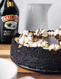 a chocolate cake topped with whipped cream and chocolate shavings next to a bottle of bailey's