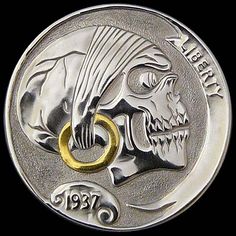 a silver coin with a skull on it's face and a gold ring in the middle