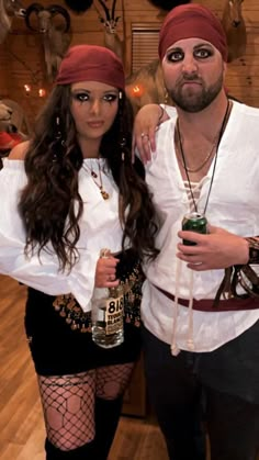 a man and woman dressed up in pirate costumes posing for a photo while holding beer cans