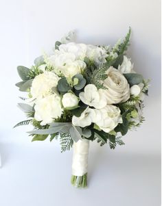 a bridal bouquet with white flowers and greenery