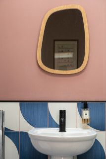 a bathroom with a sink, mirror and toilet paper dispenser in it