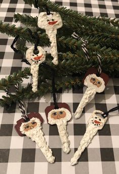 christmas ornaments made out of marshmallows are hanging from a tree branch on a checkered tablecloth