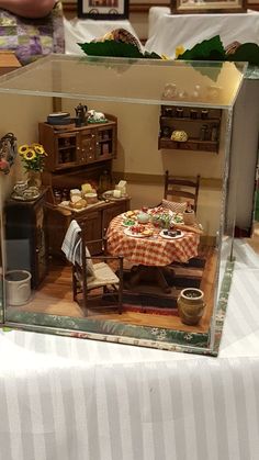 a miniature table and chairs in a glass case on a table cloth covered tablecloth